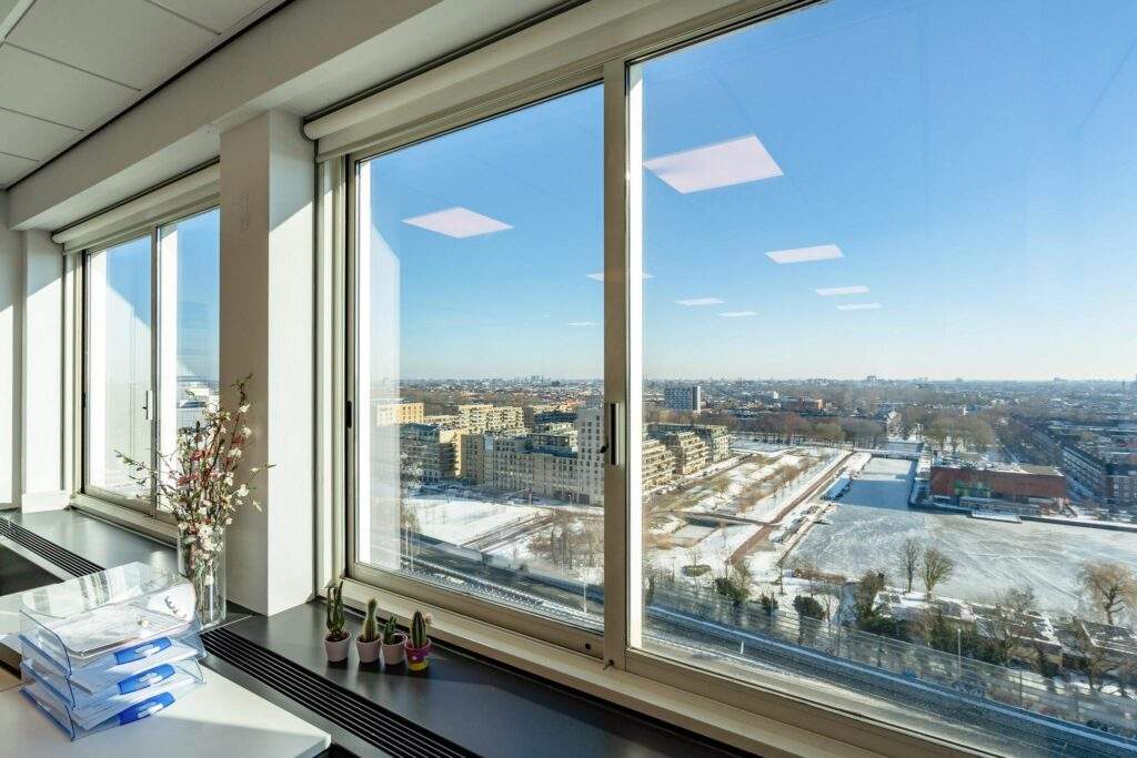 Uitzicht vanuit een hoog kantoor op het besneeuwde Koningin Wilhelminaplein in Amsterdam.